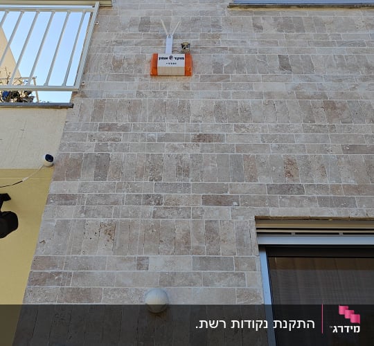 קופסת תקשורת כתומה מותקנת על קיר חיצוני